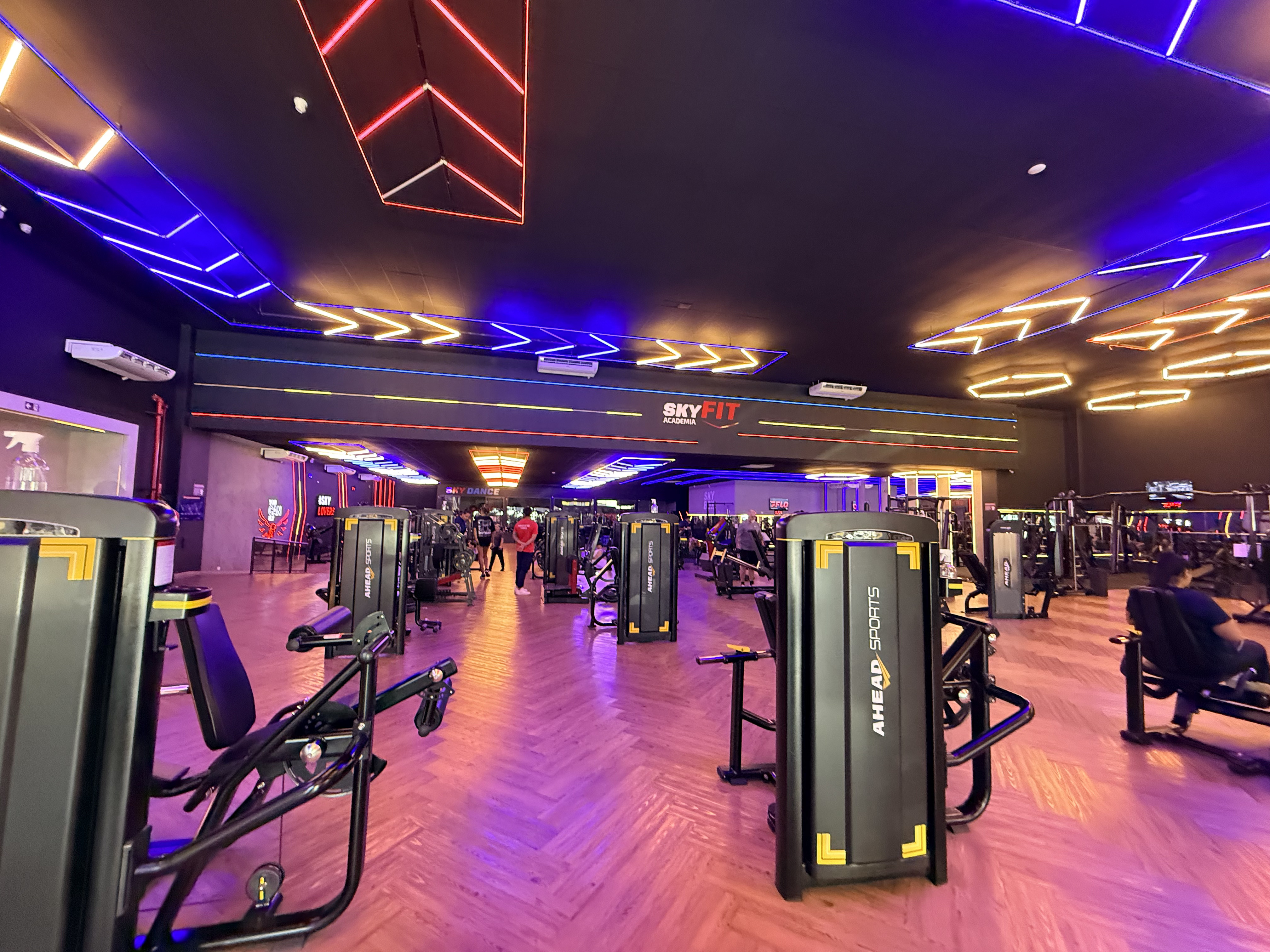 Vista ampla da academia Skyfit Boituva com aparelhos de musculação e iluminação em neon