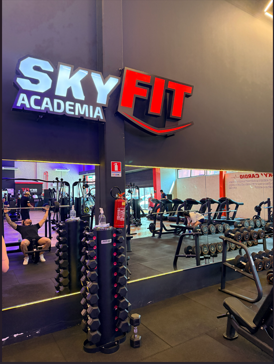 Logo Skyfit Academia na parede com halteres e espelhos